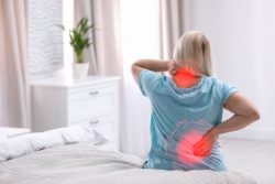 Woman sitting on bed, dealing with rheumatoid arthritis pain