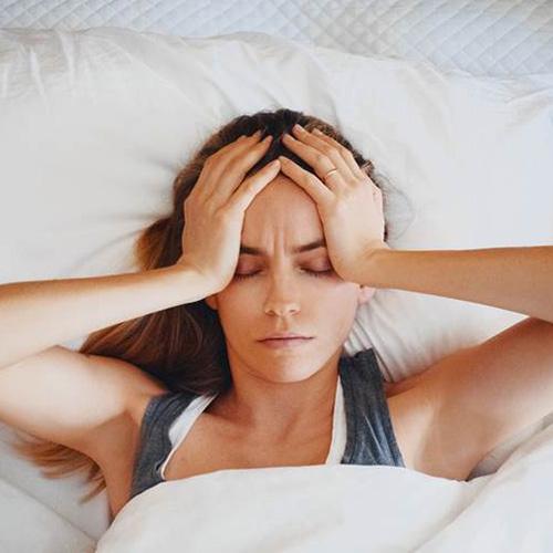 Woman in bed with headache, experiencing sleep apnea symptoms