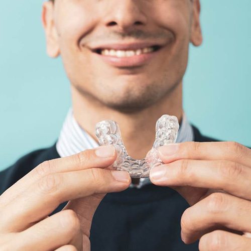 Smiling man holding custom-made oral sleep appliance