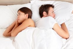 Unhappy couple lying back to back in bed