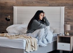 Woman sitting on bed, unhappy expression on her face