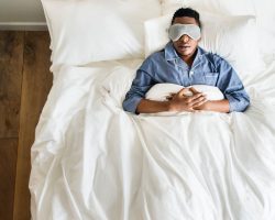 Man sleeping peacefully in bed, wearing eye mask