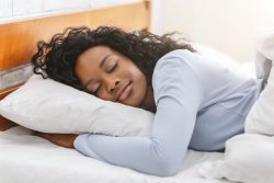 Woman sleeping peacefully in white bed sheets
