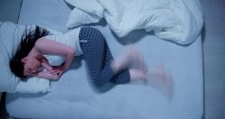 Woman lying in bed, struggling with restless leg syndrome
