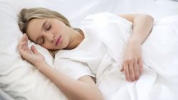 Woman sleeping peacefully in white bed linens