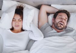 Woman covering her ears while her partner snores