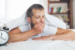 Tired man yawning in bed