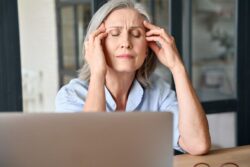 Forgetful older woman sitting at her desk